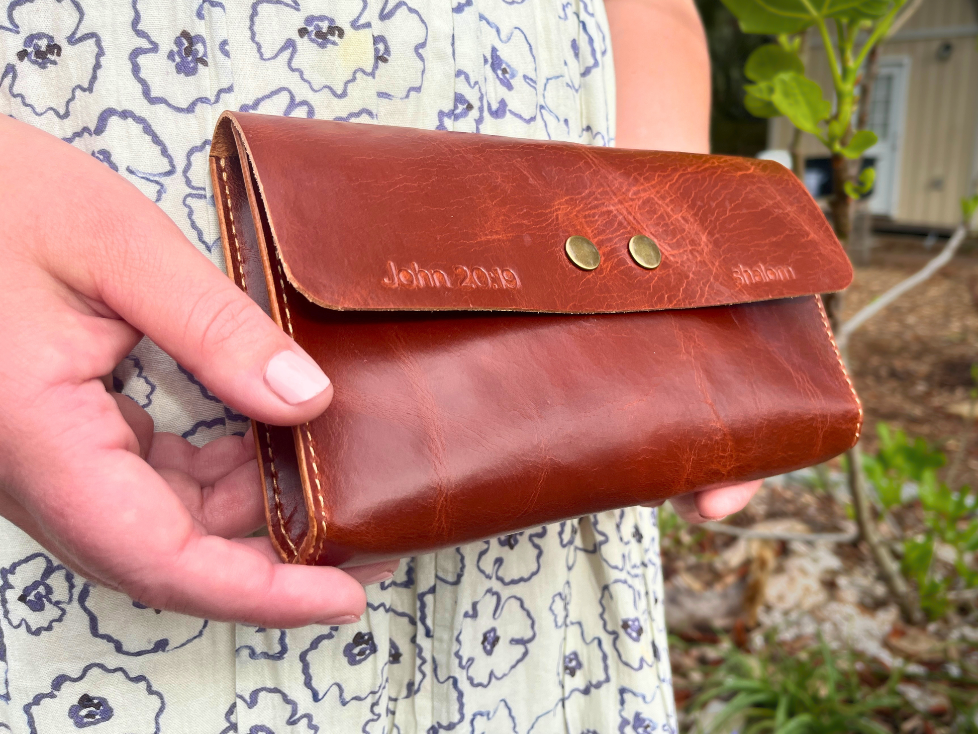 Brown leather clutch held by a person outdoors