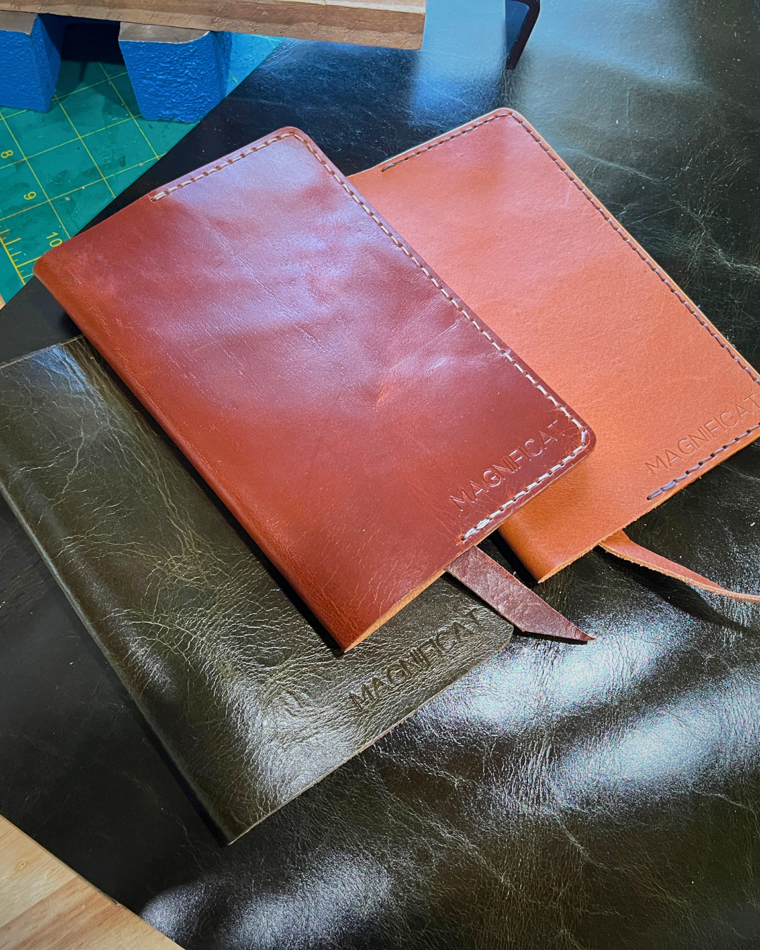 Three leather notebooks of different colors on a dark surface