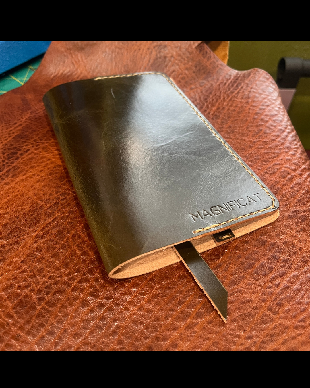 Green leather coverwith 'MAGNIFICAT' branding on a brown surface