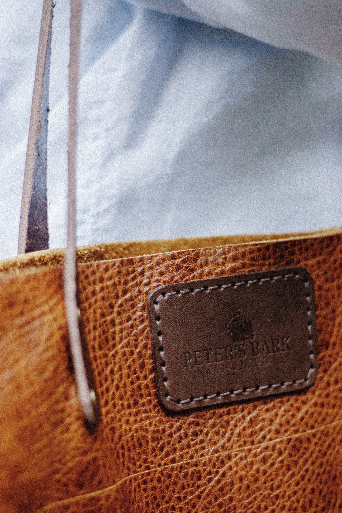 Brown leather bag with a brand label on a light blue background