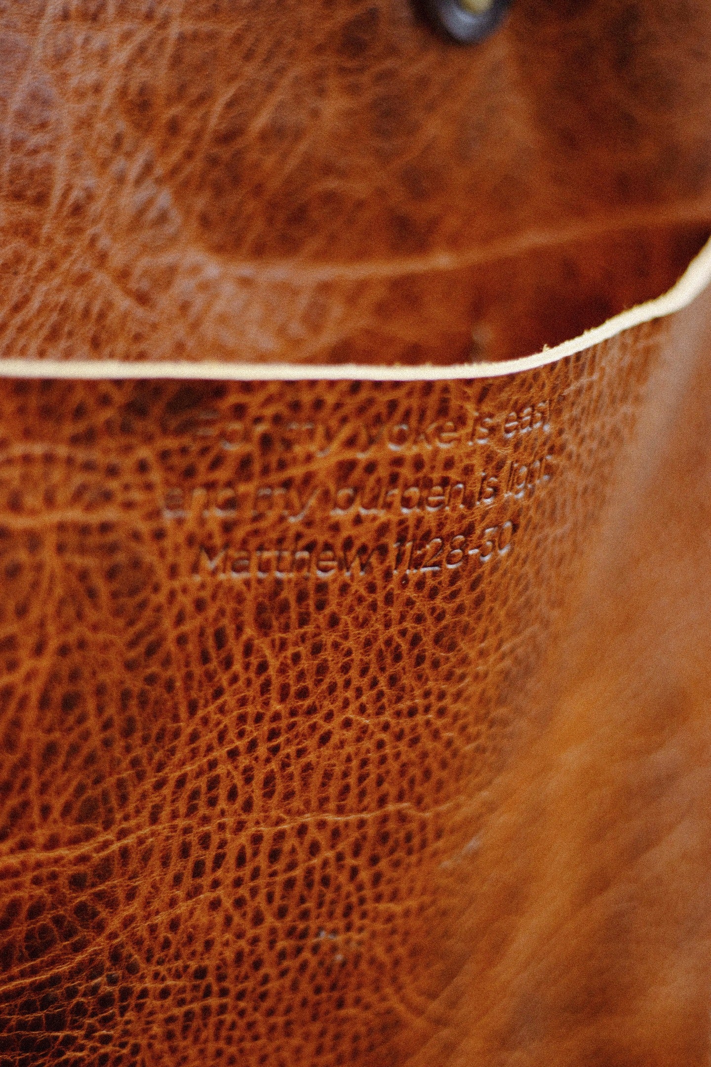 Close-up of a brown leather bag with visible scripture of Matthew 11:28-30.